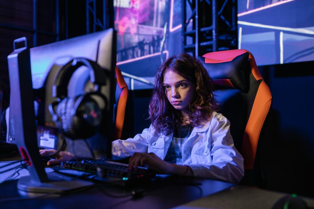 Girl sitting on a gaming set up playing video games.